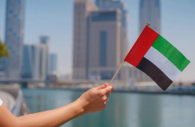 Dubai siluetine karşı BAE 'nin küçük bayrağını tutan bir kadın eli. BAE ulusal kutlama ruhunun fotoğrafı..