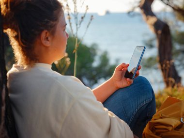 Seyahat ve aktif yaşam tarzı konsepti. Dağlarda yürüyüş yapan mutlu kadın, Fethie, Türkiye. Genç Yürüyüşçü akıllı telefon ve dijital iletişim kullanıyor. Sosyal ağda, açık havada arkadaşlarla mesajlaşmak