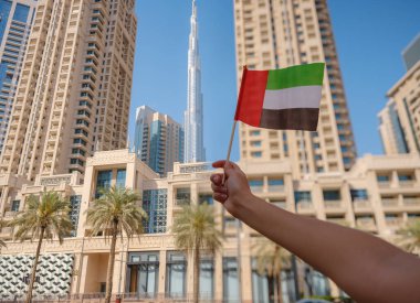 Dubai siluetine karşı BAE 'nin küçük bayrağını tutan bir kadın eli. BAE ulusal kutlama ruhunun fotoğrafı..
