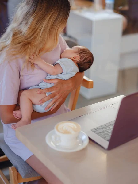 stock image Diverse people portrait. Creative businesswoman balancing work and motherhood. Beautiful young mother working with laptop computer and breastfeeding, holding and nursing her newborn baby at cafe.