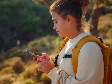 Seyahat ve aktif yaşam tarzı konsepti. Dağlarda yürüyüş yapan mutlu kadın, Fethie, Türkiye. Genç Yürüyüşçü akıllı telefon ve dijital iletişim kullanıyor. Sosyal ağda, açık havada arkadaşlarla mesajlaşmak