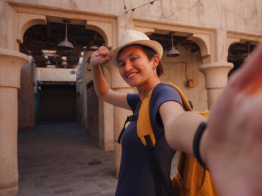 Eski Dubai, BAE 'ye turist gezisi. Asyalı kadın turist, Bur Dubai ve Creek 'in eski dar sokaklarında, Al Seef Heritage Souq' ta selfie portresi çekiyor. Seyahat ve gezi seyahat konsepti