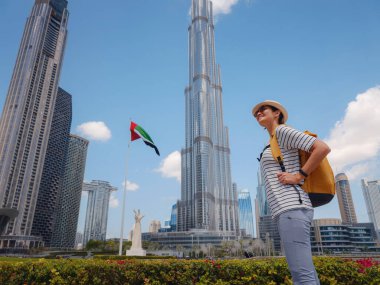 Birleşik Arap Emirlikleri 'nde iyi yolculuklar. Sarı sırt çantalı genç bir kadın güneşli yaz gününde Dubai 'de yürüyor..