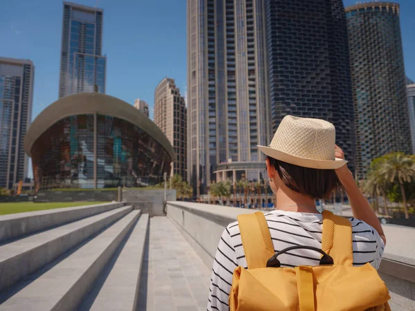 在阿拉伯联合酋长国旅途愉快 在阳光明媚的夏日 背着黄色背包在迪拜市中心散步的年轻女子 从后视镜或后视镜 — 图库照片