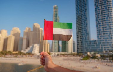Dubai siluetine karşı BAE 'nin küçük bayrağını tutan bir kadın eli. BAE ulusal kutlama ruhunun fotoğrafı..