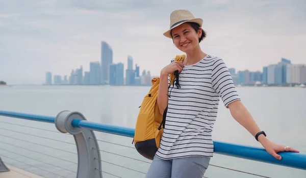 带着背包和帽子的快乐的亚洲年轻女性旅行者来到了阿拉伯联合酋长国阿布扎比市中心的城市景观 度假和旅游目的地概念 — 图库照片