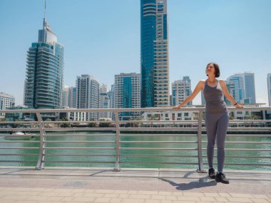 Şehir Koşusu - Asyalı kadın koşucu, Dubai marina şehir sahnesi arka planda. Kadın sporcu, fitness sporcusu, koşu antrenmanı, sağlıklı yaşam tarzı.