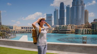 Birleşik Arap Emirlikleri 'nde iyi yolculuklar. Sarı sırt çantalı genç bir kadın güneşli yaz gününde Dubai 'de yürüyor..