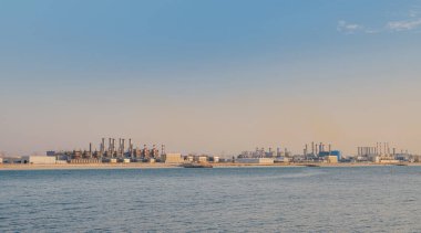 Elektrik santrali bacalarından gelen hava kirliliği. Dubai 'deki Bluewater adasının manzarası. Kentsel manzara, bitki ve fabrikaların emisyonlarından kirlenmiş atmosferi tütsüledi, renkli dumanlı boruların manzarası