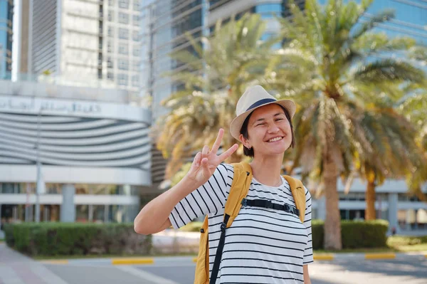 アラブ首長国連邦への旅行 バックパックとアブダビの大都市で帽子を持つ幸せな若いアジアの女性旅行者 休暇と観光地のコンセプト — ストック写真