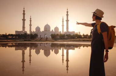 Birleşik Arap Emirlikleri 'ne seyahat, Wahat Al Karama ya da Haysiyet Vahası' nda sırt çantası ve şapkası olan mutlu Asyalı genç bayan gezgin şehitleri için kalıcı anıt ve Shaikh Zayed Büyük Camii..