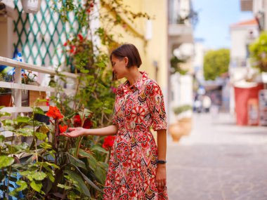 Yunanistan 'ın Rodos adasına yaz gezisi. Etnik kırmızı elbiseli genç Asyalı kadın Rodos şehrinin rahat renkli sokaklarında yürüyor. Turizm, tatil, solo seyahat ve keşif konsepti