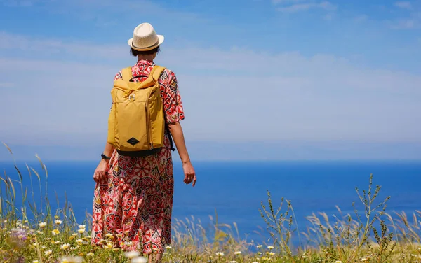 stock image summer trip to Rhodes island, Greece. Young Asian woman in ethnic red dress and yellow backpack walk to viewpoint over city of Rhodes. Tourism, vacation, solo travel and discovery concept