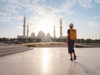 Birleşik Arap Emirlikleri 'ne seyahat, Wahat Al Karama ya da Haysiyet Vahası' nda sırt çantası ve şapkası olan mutlu Asyalı genç bayan gezgin şehitleri için kalıcı anıt ve Shaikh Zayed Büyük Camii..