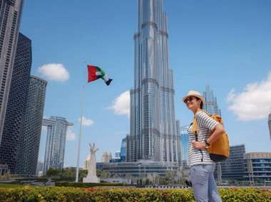 Birleşik Arap Emirlikleri 'nde iyi yolculuklar. Sarı sırt çantalı genç bir kadın güneşli yaz gününde Dubai 'de yürüyor..