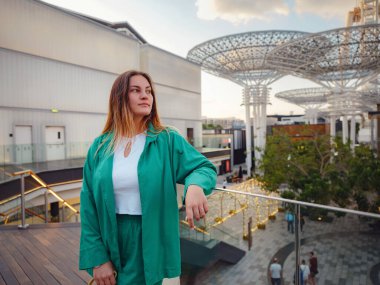Yeşil takım elbiseli genç kadın Dubai, Dubai Marina Bölgesi Mavi Su Adası sokaklarında yürüyor. Birleşik Arap Emirlikleri gezi konsepti. Başarılı bir gurbetçi olma fikri, başka bir ülkeye taşınma, çalışma vizesi