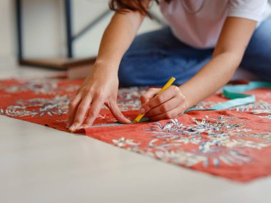 Dikiş makinesi için eskiz çizgilerinde makas desenli elbise detaylarıyla konsantre olmuş genç kadın terzi kesikleri. Bir terzinin işyeri. El yapımı konsept.