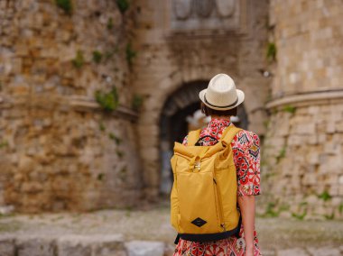 Yunanistan 'ın Rodos adasına yaz gezisi. Etnik kırmızı elbiseli genç Asyalı kadın Rodos sokaklarında yürüyor. Bayan gezgin Güney Avrupa 'yı ziyaret ediyor. Unesco Dünya Mirası Bölgesi.