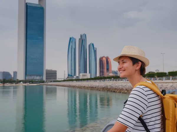 带着背包和帽子的快乐的亚洲年轻女性旅行者来到了阿拉伯联合酋长国阿布扎比市中心的城市景观 度假和旅游目的地概念 — 图库照片