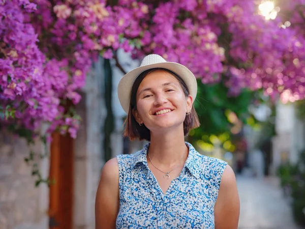 stock image Blooming bougainvillea, streets of the old town of Bodrum, Turkey. Happy traveler woman in white elegant outfit walking by romantic streets . Summer travelling