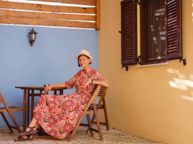 Yunanistan 'ın Rodos adasına yaz gezisi. Etnik kırmızı elbiseli genç Asyalı kadın Rodos şehrinin rahat renkli sokaklarında yürüyor. Turizm, tatil, solo seyahat ve keşif konsepti