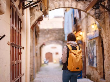 Yunanistan 'ın Rodos adasına bahar ya da sonbahar gezisi. Genç Asyalı kadın gün batımında Kale Şövalyeleri Sokağı 'nda yürüyor. Bayan gezgin Güney Avrupa 'yı ziyaret ediyor. Unesco Dünya Mirası Bölgesi.