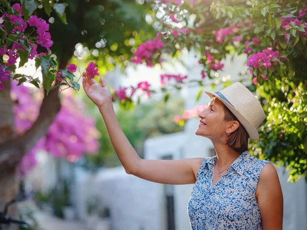 Blooming bougainvillea, streets of the old town of Bodrum, Turkey. Happy traveler woman in white elegant outfit walking by romantic streets . Summer travelling