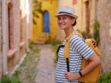 Yunanistan 'ın Rodos adasına yaz gezisi. Çizgili tişörtlü ve şapkalı genç Asyalı kadın Şövalyeler Kalesi 'nde yürüyor. Bayan gezgin Güney Avrupa 'yı ziyaret ediyor. Unesco Dünya Mirası Bölgesi