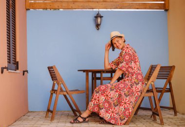 Yunanistan 'ın Rodos adasına yaz gezisi. Etnik kırmızı elbiseli genç Asyalı kadın Rodos şehrinin rahat renkli sokaklarında yürüyor. Turizm, tatil, solo seyahat ve keşif konsepti