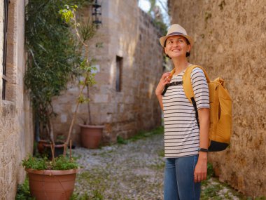 Yunanistan 'ın Rodos adasına yaz gezisi. Çizgili tişörtlü ve şapkalı genç Asyalı kadın Şövalyeler Kalesi 'nde yürüyor. Bayan gezgin Güney Avrupa 'yı ziyaret ediyor. Unesco Dünya Mirası Bölgesi