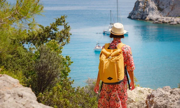 戴帽子的亚洲女人看到了地中海蓝色海湾的景色 旅行和度假的概念 安东尼奎恩湾水晶清澈的水在罗得岛 最美丽的海滩 图库图片