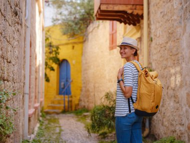 Yunanistan 'ın Rodos adasına yaz gezisi. Çizgili tişörtlü ve şapkalı genç Asyalı kadın Şövalyeler Kalesi 'nde yürüyor. Bayan gezgin Güney Avrupa 'yı ziyaret ediyor. Unesco Dünya Mirası Bölgesi