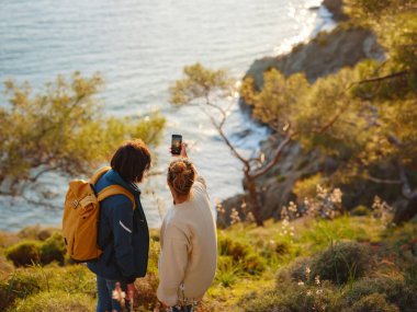 Türkiye gezisi, iki kadın gün batımının keyfini çıkarıyor ve Fethiye şehrinde selfie çekiyor. Birlik, akıl sağlığı, ekolojik seyahat. Dağlarda yürüyüş, seyahat, güzel anlar, dijital detoks.