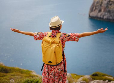 Şapkalı Asyalı kadın Akdeniz 'deki gök mavisi Bay manzarasına bakıyor. Seyahat ve tatil konsepti. Anthony Quinn körfezi, Yunanistan 'ın Rodos adasında berrak suyla birlikte. En güzel kumsal.