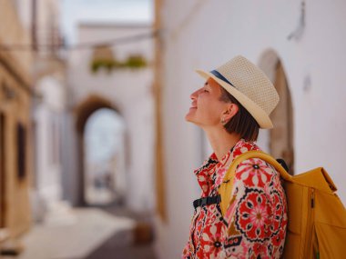 Yunan Adaları 'nda güneşli bir günün tadını çıkaran boho elbiseli güzel bir Asyalı kadın. Lindos 'a seyahat, Akdeniz adaları turizm sezonu. Yunanistan 'da tatilde olan turist kadın Lindos sokaklarında yürüyor.