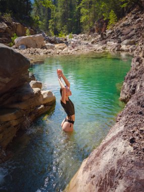 Sıcak bir yaz gününde Türkiye seyahati, Akdeniz bölgesi. Mayolu genç bir kadın dağ nehrinde eğleniyor. Açık hava, seyahat, aktif yaşam tarzı, yaz tatili kavramı.