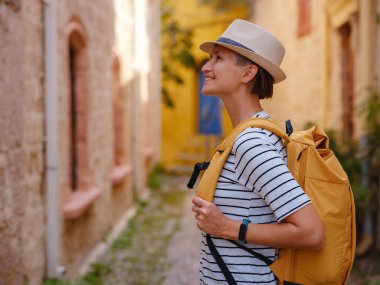 Yunanistan 'ın Rodos adasına yaz gezisi. Çizgili tişörtlü ve şapkalı genç Asyalı kadın Şövalyeler Kalesi 'nde yürüyor. Bayan gezgin Güney Avrupa 'yı ziyaret ediyor. Unesco Dünya Mirası Bölgesi