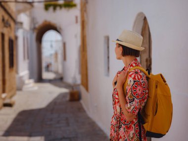 Yunan Adaları 'nda güneşli bir günün tadını çıkaran boho elbiseli güzel bir Asyalı kadın. Lindos 'a seyahat, Akdeniz adaları turizm sezonu. Yunanistan 'da tatilde olan turist kadın Lindos sokaklarında yürüyor.