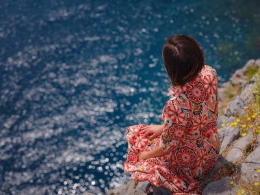 Yunan Adaları 'nda güneşli bir günün tadını çıkaran güzel mutlu kadın. Yunanistan 'a seyahat, turizm sezonu dışında Akdeniz adaları. Hayatın tadını çıkarmak ve denize bakmak. Turkuaz deniz arkaplanı.