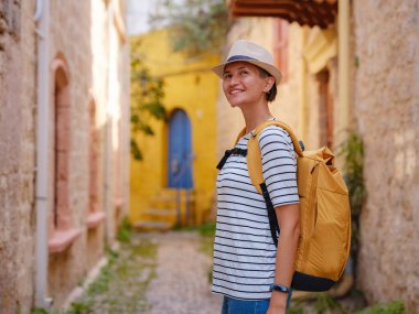 Yunanistan 'ın Rodos adasına yaz gezisi. Çizgili tişörtlü ve şapkalı genç Asyalı kadın Şövalyeler Kalesi 'nde yürüyor. Bayan gezgin Güney Avrupa 'yı ziyaret ediyor. Unesco Dünya Mirası Bölgesi