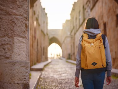 Yunanistan 'ın Rodos adasına bahar ya da sonbahar gezisi. Genç Asyalı kadın gün batımında Kale Şövalyeleri Sokağı 'nda yürüyor. Bayan gezgin Güney Avrupa 'yı ziyaret ediyor. Unesco Dünya Mirası Bölgesi.