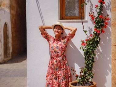 Yunan Adaları 'nda güneşli bir günün tadını çıkaran boho elbiseli güzel bir Asyalı kadın. Lindos 'a seyahat, Akdeniz adaları turizm sezonu. Yunanistan 'da tatilde olan turist kadın Lindos sokaklarında yürüyor.