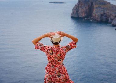 Yunan Adaları 'nda güneşli bir günün tadını çıkaran güzel mutlu kadın. Yunanistan 'a seyahat, turizm sezonu dışında Akdeniz adaları. Hayatın tadını çıkarmak ve denize bakmak. Turkuaz deniz arkaplanı.