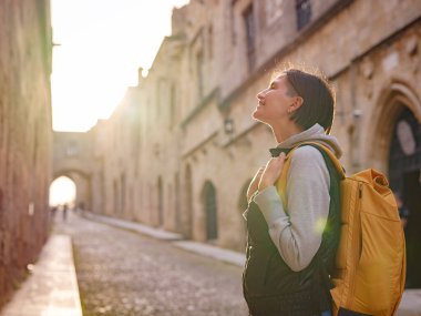 Yunanistan 'ın Rodos adasına bahar ya da sonbahar gezisi. Genç Asyalı kadın gün batımında Kale Şövalyeleri Sokağı 'nda yürüyor. Bayan gezgin Güney Avrupa 'yı ziyaret ediyor. Unesco Dünya Mirası Bölgesi.