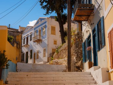 Ege Denizi 'ndeki Rodos' tan tatil yapan Yunanistan 'daki Symi Adası. Symi Körfezi 'ndeki renkli neoklasik evler. Tatil gezisi geçmişi. Tepeden güzel dar bir sokak Sevimli Yunan evleri arasında