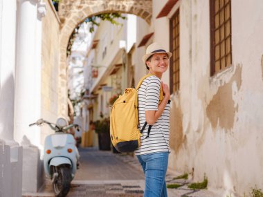 Yunanistan 'ın Rodos adasına yaz gezisi. Çizgili tişörtlü ve şapkalı genç Asyalı kadın Şövalyeler Kalesi 'nde yürüyor. Bayan gezgin Güney Avrupa 'yı ziyaret ediyor. Unesco Dünya Mirası Bölgesi