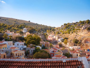 Symi Adası, Yunanistan. Yunanistan, Ege Denizi 'ndeki Rodos adalarından tatil yapıyor. Günbatımında bir Yunan adasının yamaçlarında renkli neoklasik güzel evler. Tatil seyahat arkaplanı.