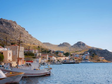 Symi ya da Simi adası limanı, klasik gemi yatları, ada tepelerindeki evler, Ege Körfezi. Yunanistan adaları Rodos adasından tatil turları düzenliyor. Symi, Yunanistan, Dodecanese.
