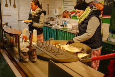 Düsselldorf, Almanya - 13 Aralık 2022: Kadınlar, petrolde kızartılmış geleneksel bir Macar ekmeği olan langosh 'u hazırlıyorlar. Noel pazarında yemek hazırlığı
