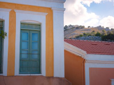 Pencereler, kapılar, Simi Adası 'ndaki eski evlerin balkonları. Yunanistan, Ege Denizi 'ndeki Rodos adalarından tatil yapıyor. Symi Körfezi 'ndeki renkli neoklasik evler. Tatil seyahat arkaplanı.